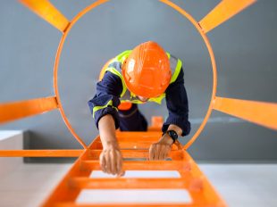 operaio con casco di protezione sale su una scala