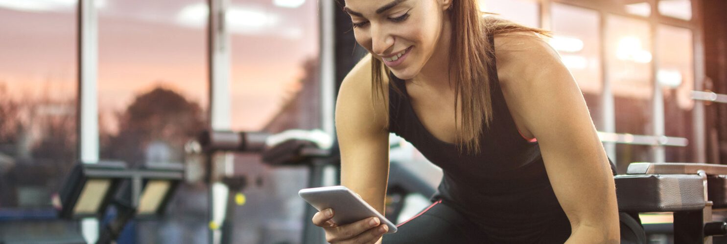 ragazza in palestra con pesi e smartphone in mano