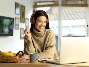 ragazza sorridente seduta davanti al pc con cuffie rosse