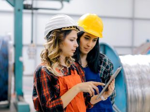due donne con casco di protezione consultano tablet