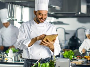 chef sorridente gestisce ordinazioni con tablet