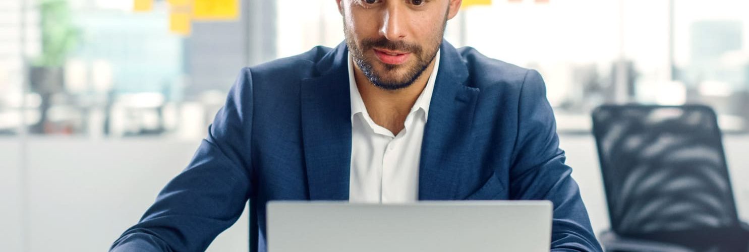 giovane uomo in giacca blu seduto alla scrivania con pc