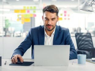 giovane uomo in giacca blu seduto alla scrivania con pc