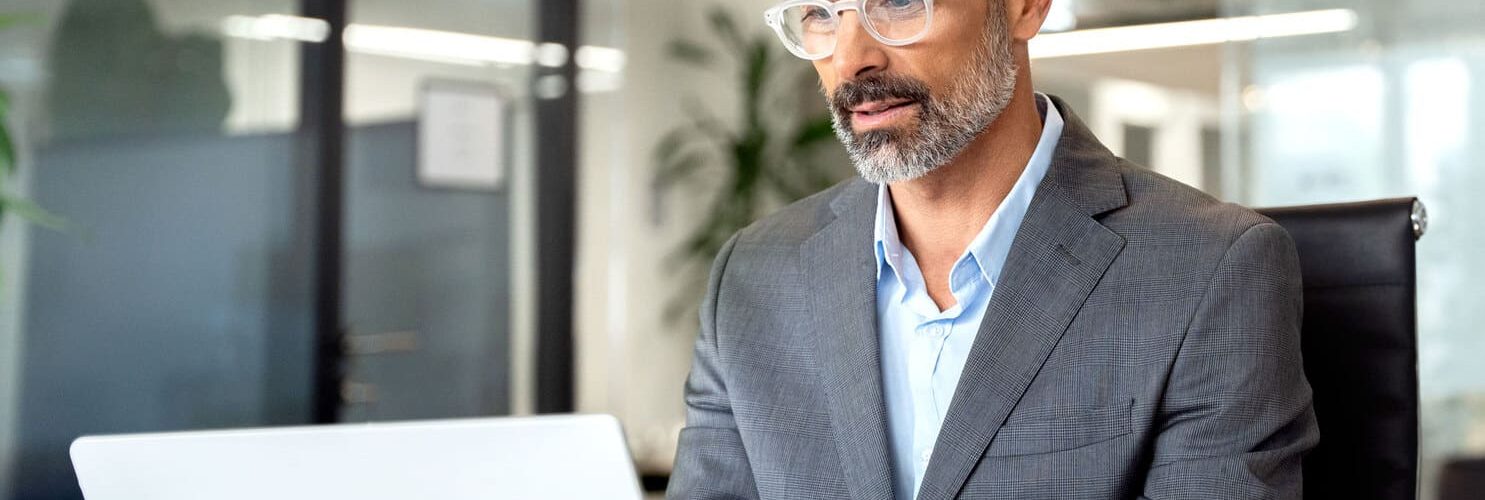 persona in giacca seduta in ufficio di fronte a pc