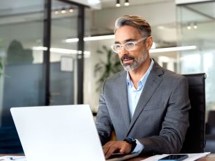 persona in giacca seduta in ufficio di fronte a pc
