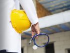 persona con camice da medico tiene in mano un casco di sicurezza