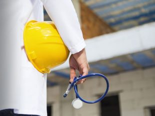 persona con camice da medico tiene in mano un casco di sicurezza